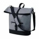 A gray crossbody bag with a black adjustable strap, black base, and black zipper pocket on the front. It has a flap-top closure with a buckle and a small handle on top.