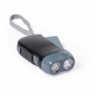 A black and gray handheld flashlight with dual lenses and a strap. It features a hand-crank mechanism for power generation, with the crank visible folded on the side. The flashlight is designed for portable use.