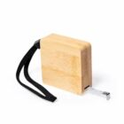 A wooden measuring tape with a black wrist strap. The tape partially extends from the rectangular wooden case, displaying measurement units. The tape measure rests against a white background.