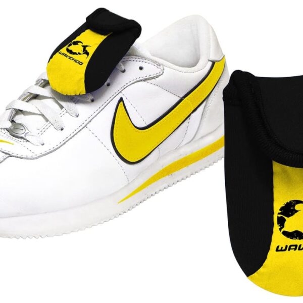 White sneaker with yellow accents, featuring a yellow swoosh logo on the side. A black and yellow shoe tongue cover with Wavehog written on it is shown separately.