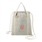 Beige drawstring tote bag with abstract red and blue design and TROKA STUDIOS text.