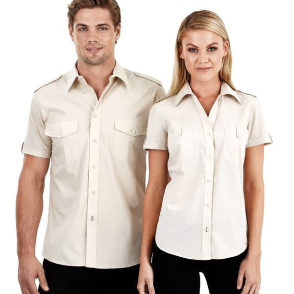 A man and a woman wearing matching beige short-sleeve button-up shirts with black pants stand side by side against a plain white background. Both shirts feature front pockets with flaps.