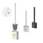 Three toilet brushes with holders in white, light gray, and black are displayed. One brush shows a close-up of its flexible bristles. The holders have different logos: a heart, leaf, and flower.
