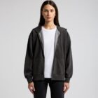 Woman in black zip-up hoodie over white t-shirt, standing against a plain background.