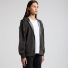 Woman wearing a black zip-up hoodie over a white t-shirt, standing against a plain background.