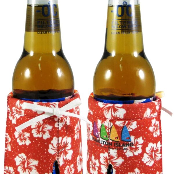 Two bottles of yellow beverage with blue caps, each wrapped in red floral-patterned fabric covers with drawstrings. The design features white hibiscus flowers and colorful sailboats.