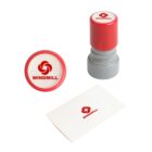 A red and gray rubber stamp featuring a red windmill logo and the word WINDMILL is shown. The stamp is displayed standing upright, with a stamped card and the stamps top view beside it.