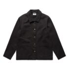 A black, long-sleeved jacket with a collared neckline and front button closure. It features two chest pockets and two lower pockets, creating a minimalist, structured look.