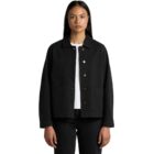 A person with long dark hair wears a black jacket over a white shirt and black pants. The jacket has buttons and pockets, and the person stands against a plain white background.