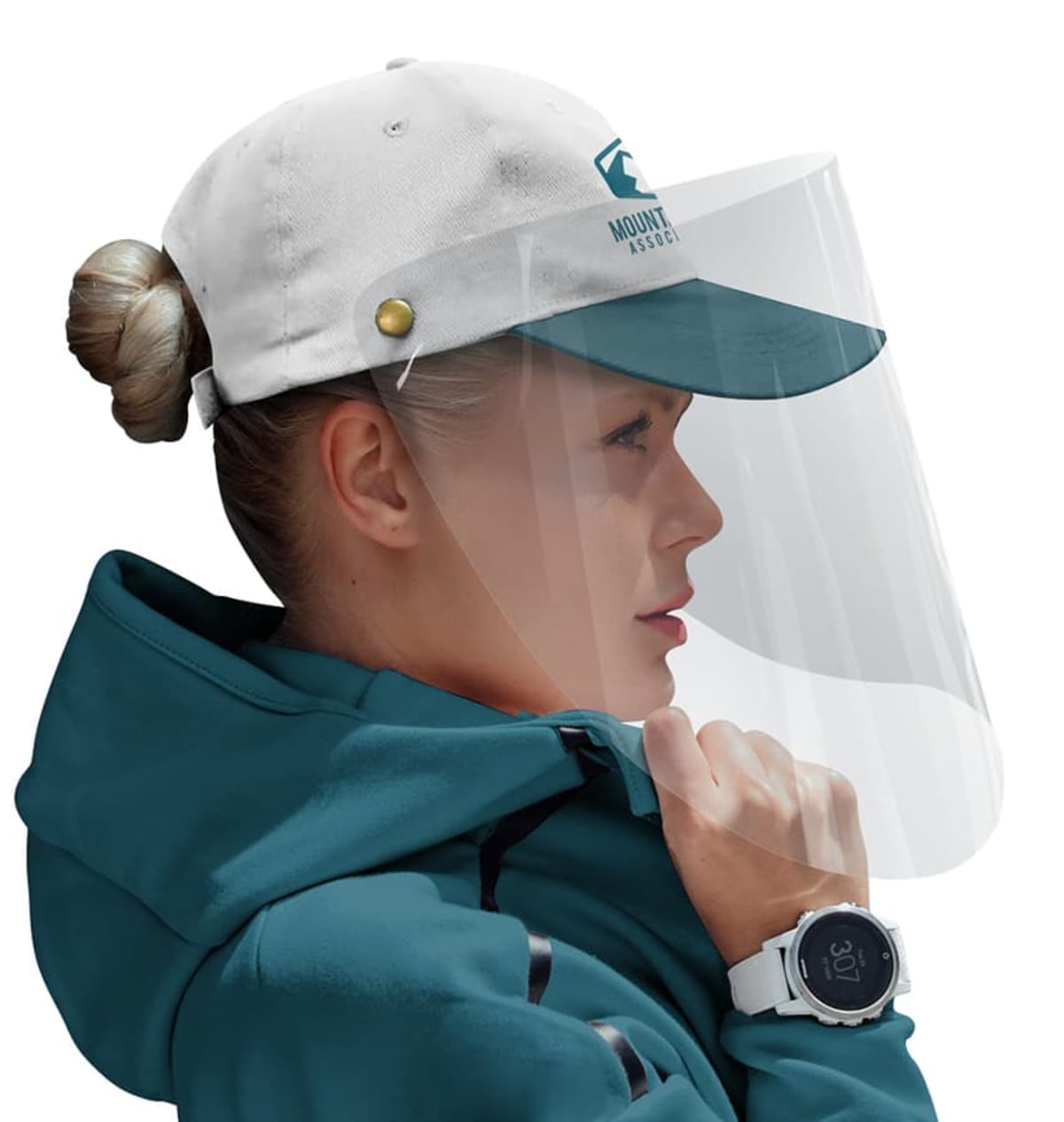 A person wearing a teal jacket, a white and teal baseball cap with a logo, and a transparent face shield. Their hair is tied in a bun, and they are wearing a smartwatch.