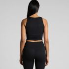 A person with long black hair is wearing a black sleeveless top and black leggings, standing with their back to the camera against a plain gray background.