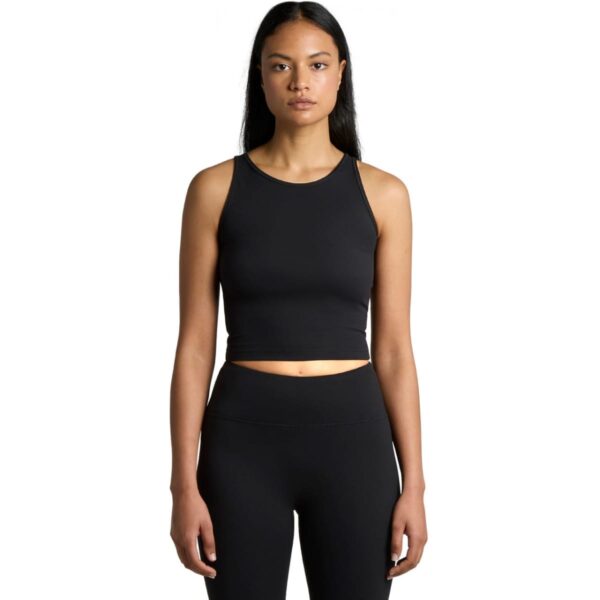 A person wearing a black sleeveless crop top and black leggings stands against a plain white background, facing the camera.