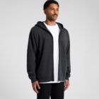 Man wearing a black zip-up hoodie over a white t-shirt, standing against a plain background.