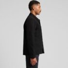 Man in a black jacket and pants standing in profile against a gray background.