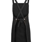 A black denim apron with cross-back straps and a tie waist. The apron features a sleek, minimalist design with a slightly worn look, emphasizing functionality and style.