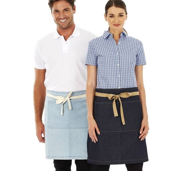 A man and a woman stand side by side, both wearing aprons. The man is in a white polo and light blue apron, while the woman wears a checkered shirt and dark blue apron. Both smile at the camera against a white background.