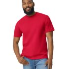 A person with a beard is smiling while wearing a bright red T-shirt and blue jeans. They are standing against a plain white background.