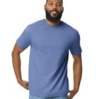 A man with a beard is smiling and posing with his hands on his hips. He is wearing a plain blue T-shirt and blue jeans. The background is plain white.