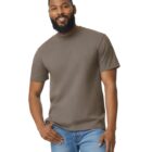 A man with a beard smiles, wearing a plain olive green T-shirt and blue jeans against a plain white background.