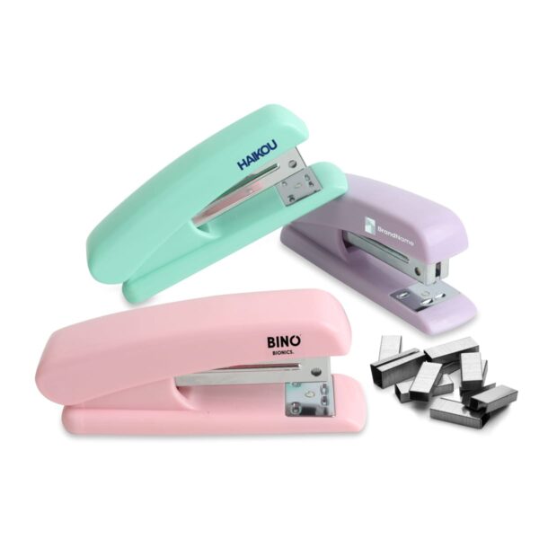 Three colorful staplers in mint green, lavender, and pink are displayed. Each stapler has a small name on it, with a pile of silver staples to the side.