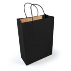 A black paper shopping bag with two black handles, standing upright on a light surface. The interior of the bag is brown, contrasting with the black exterior. Shadows beneath the bag suggest natural lighting.