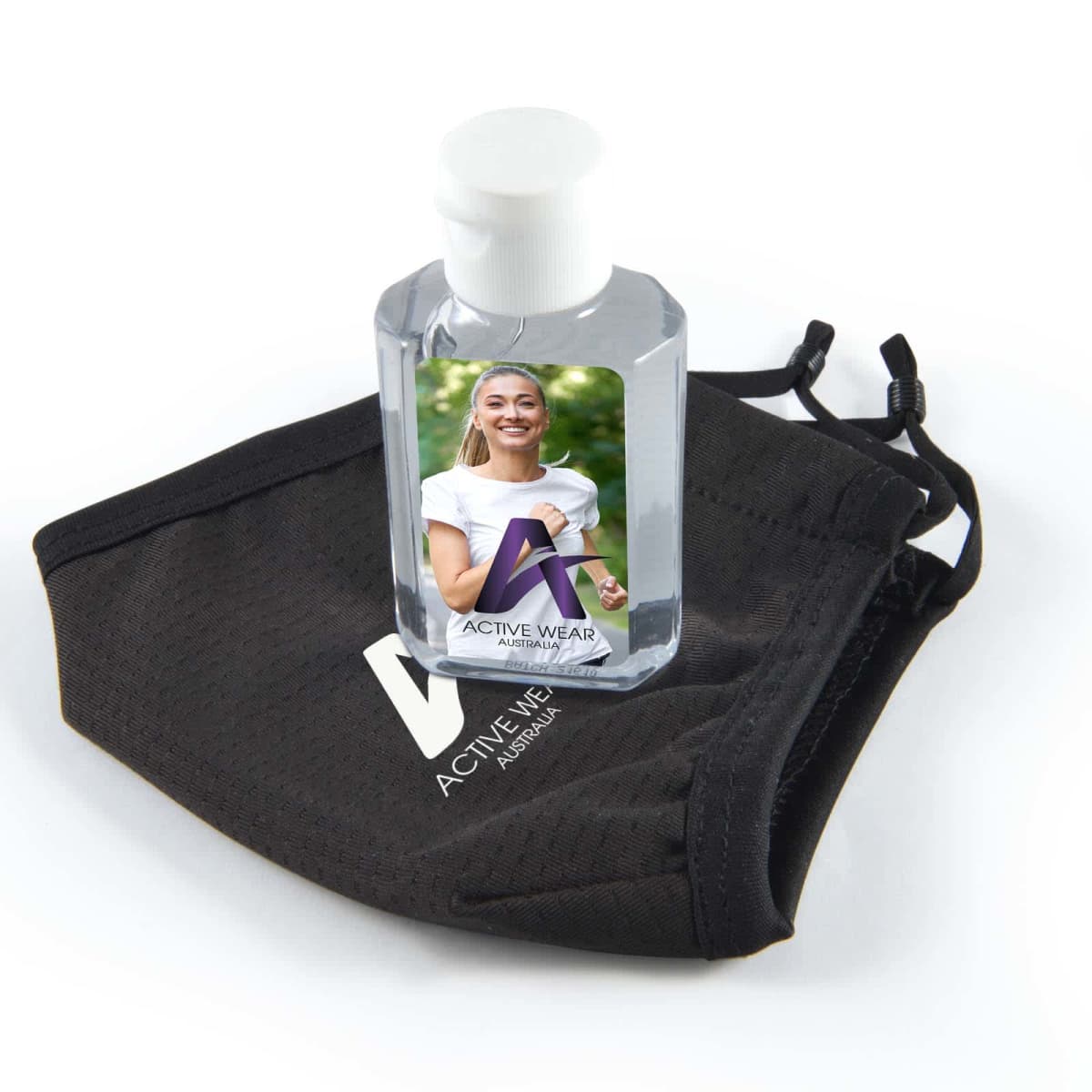 A small bottle of hand sanitizer placed on a black fabric face mask. The sanitizer bottle features a label with the letter A and an image of a smiling person.