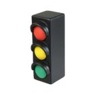 A small model traffic light with three colored lights, red on top, yellow in the middle, and green at the bottom, all housed in a rectangular black casing on a plain white background.