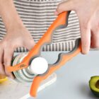 A person uses an orange and gray jar opener to twist open a bottle. A lemon slice and half an avocado are on the table nearby. The person is wearing a striped apron.