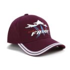 A maroon baseball cap with white embroidered jets and the words Volontaire Faire on the front. The cap features white stripes along the edge of the brim.
