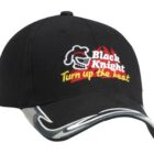 A black baseball cap featuring an embroidered logo with a stylized knight helmet and the text Black Knight in red and Turn up the heat in yellow. The brim has a curved silver and black design.