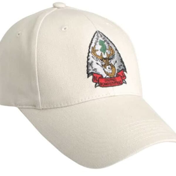 A beige baseball cap featuring an embroidered patch with a deer head and a red ribbon. The patch is shaped like an arrowhead with green and white colors in the background.