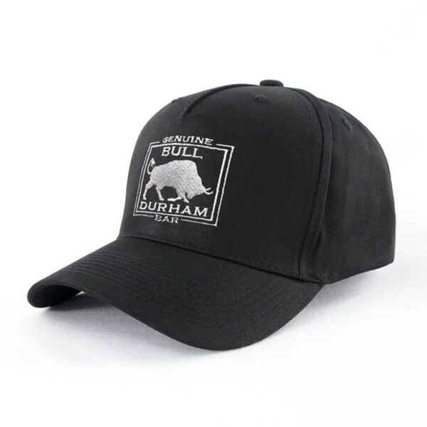 A black baseball cap featuring an embroidered design of a bull within a square outline, with the words Genuine Bull Durham Bar above and below the image. The cap is set against a plain white background.