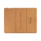 A cork-textured foldable mouse mat with the words Foldable Mouse Mat and Oaky printed on it. The mat is divided into three sections, suggesting its foldable design. An icon, possibly for wireless charging, is also visible on the left side.