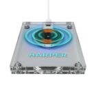 A transparent wireless charging pad with glowing blue and purple highlights, featuring the name HARPER in capital letters. It is connected via a white cable.