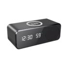 A sleek black digital clock with an LED display showing 12:30 and 59. It has a speaker on the right side and a wireless charging symbol on top.