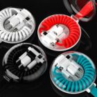 Four round portable charging cable cases are displayed. Each case contains a coiled cable and multiple connectors. The cases are in different colors: black, red, turquoise, and white, each with a transparent lid.