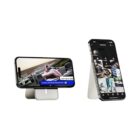 Two mobile phones on stands: the left phone displays a racing game with a car on track, while the right phone shows a grid of apps and images. Both stands are sleek and minimalist in design.