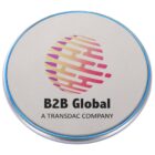 A wireless charging pad with a circular beige surface featuring the logo and text B2B Global A Transdac Company. The logo consists of an abstract, multicolored globe design. A blue LED ring encircles the edge of the pad.