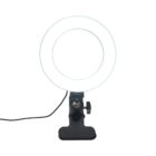 A circular LED ring light attached to a black stand with a wired power cord extending from the base. The stand has an adjustable clamp for attachment to surfaces. The ring light emits a bright, even glow.