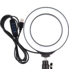 A circular LED ring light with a USB cable attached. The cable includes an inline control panel with buttons for power, brightness, and lighting modes. The ring light is mounted on an adjustable stand.