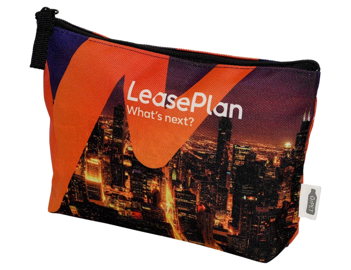A colorful zippered pouch with the words LeasePlan Whats next? printed on it. The background features an urban cityscape at night with bright lights. The pouch has a black zipper and a fabric tag on the side.