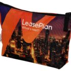 A zippered pouch featuring a cityscape at night with orange and purple accents. The text LeasePlan Whats next? is printed on it. The pouch has a black zip and a white tag with a recycle symbol on the side.