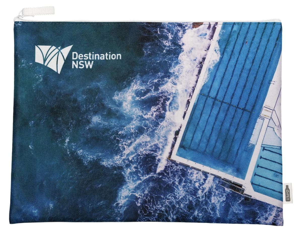 A zippered pouch featuring an aerial view of a coastal swimming pool with ocean waves crashing against it. The words Destination NSW are printed in white in the top left corner.