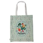 A light green reusable tote bag featuring a Farmers Market logo with illustrations of vegetables and fruits like broccoli, corn, and tomato. The background has a pattern of small vegetables and fruits. The bag has white handles.