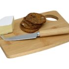 Cheese, crackers, and a cheese knife on a wooden cutting board with a hole handle.
