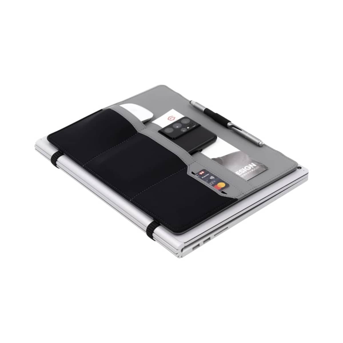 A gray tablet cover with pockets is shown, holding a smartphone, credit cards, and a pen. The cover is placed on a closed laptop, with its utilitarian design displayed, emphasizing organization and convenience.