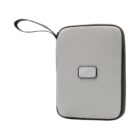 A gray fabric-covered electronic device with rounded edges and a small rectangular button on its surface. It features a black edge and a wrist strap for easy carrying.