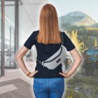 A woman stands with her back to the camera, indoors on the left and outdoors on the right. She wears a black shirt and blue jeans, with a gray fanny pack. The indoor scene is an office, while the outdoor scene features a car and mountain landscape.