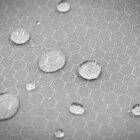 Water droplets on a gray hexagonal-patterned surface, showcasing the fabrics water-repellent feature.