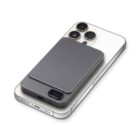 A smartphone with a triple camera setup on the back, lying face down. A gray, rectangular power bank with a digital display showing 99 is magnetically attached to the phones back.